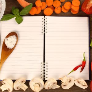 Rezeptsammlung Rezeptheft liegt auf einem Tisch. Rundherum liegt Gemüse